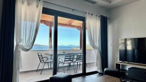 sala de estar con balcón con mesa y sillas en Thea Penthouse with private parking, en Sarandë