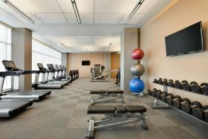 a gym with rows of exercise equipment and a flat screen tv at Aloft Dallas Love Field in Dallas