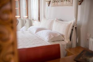 a bed with white sheets and pillows in a room at Traditional Mansion Kliaris in Ayía Kiriakí +2 photos