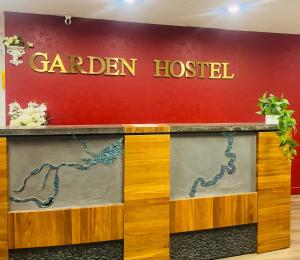 a sign for a garden hospital on a wall at Garden Hostel in Auckland