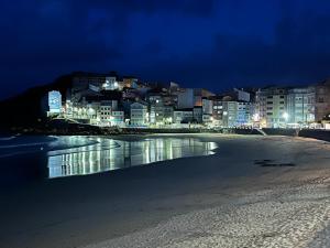 a view of a beach at night with buildings at Caballito de mar in Malpica