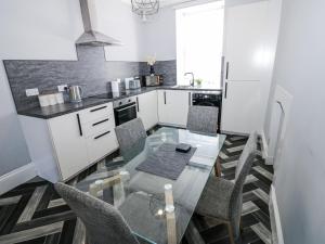 a small kitchen with a glass table and chairs at Lowther House in Whitehaven