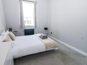 a white bedroom with a bed and a window at Lowther House in Whitehaven