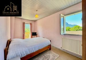 a bedroom with a bed and a large window at Le Montagnard in Marignier