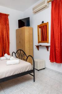 - une chambre avec un lit, un miroir et des rideaux rouges dans l'établissement John's economy, à Naxos Chora