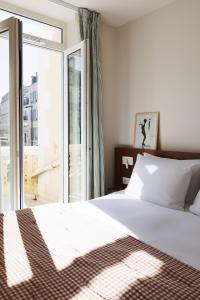 a bedroom with a bed and a large window at Alfred Hotels Les Halles in Biarritz
