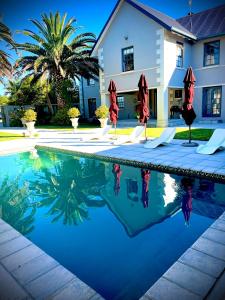 a swimming pool with umbrellas in front of a house at Stoneridge Large Family Cottage in Plettenberg Bay