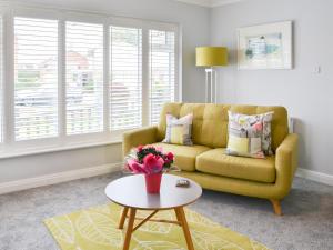 a living room with a yellow couch and a table at Poppys' Place in Sewerby