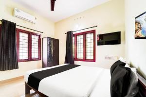 a bedroom with a bed and a tv and windows at Hotel O Nettoor Near Lakeshore Hospital in Cochin