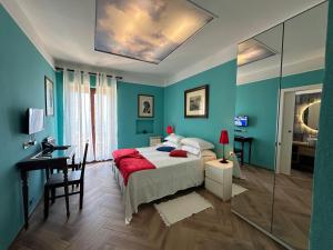 a blue bedroom with a bed and a desk and a mirror at Isoco House in Taormina