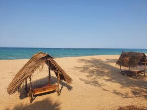 two straw umbrellas on a beach with the ocean at UK Lounge Resort in Trincomalee