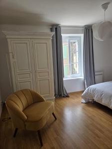 a bedroom with a chair and a bed and a window at La belle échappée in Recloses