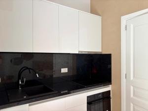 a kitchen with white cabinets and a black counter top at Agios Nikolaos Open Living Suite in Agios Nikolaos