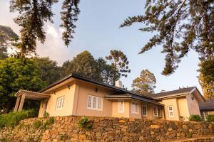 a house behind a stone wall at Jetwing Oatlands Bungalow - Whole Villa in Nuwara Eliya +6 photos