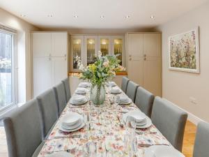 un comedor con una mesa larga con un jarrón de flores en Whydown Cottage, en Hooe