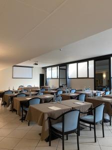 a dining room with tables and chairs and windows at Hotel Gardenia Fiera in Cermenate
