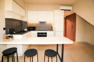 a kitchen with a white counter and two stools at Villa El Mar in Gerakini
