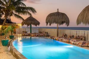 a swimming pool with umbrellas and the ocean at ZAN Paradise Beach in Bwejuu