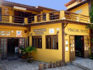 un bâtiment jaune avec un panneau indiquant l'hôpital wizardsisk dans l'établissement Maresias Hostel & Suites, à Maresias