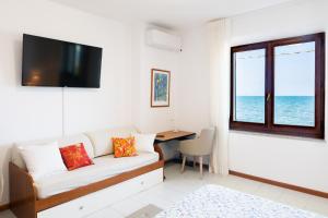 a living room with a couch and a desk and a window at Villa Fausta in La Maddalena