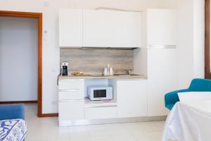 a kitchen with white cabinets and a microwave at Villa Fausta in La Maddalena +7 photos