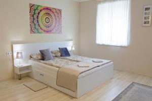 a white bedroom with a bed with blue pillows at Szíriusz Apartmanház in Gyula