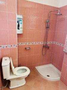 e bagno piastrellato rosa con servizi igienici e doccia. di Blue Escape Apartment Lungo Mare a Vlorë