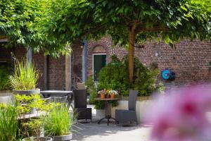 a patio with chairs and a table with plants at Hoeve de Binnenplaets - Appartementen - Glamping - Familieverblijf in Schimmert