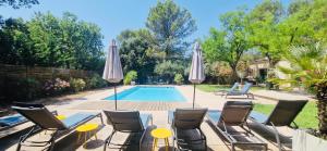 un patio avec chaises et parasols à côté d'une piscine dans l'établissement La Maison du Soleil, à Saint-Didier