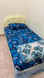 ein Bett mit einer blau-weißen Bettdecke darauf in der Unterkunft Cozy Vibes Hostel in Muscat