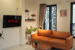 an orange couch in a living room with a window at Migo Housing - Lift Access - Hanoi Beer Street - Central and Spacious - Ensuite Kitchen - Ensuite Bathroom in Hanoi