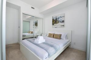 ミシサガにあるDowntown Toronto Condo walk to CN Tower and Rogers centerの白いベッドルーム(大型ベッド1台、鏡付)