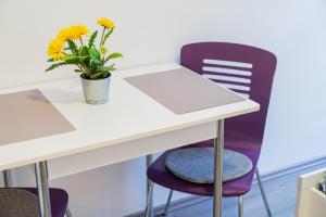 a white desk with a vase of flowers and a purple chair at Flex SelfCheckIns 130 - Zagreb - Studio Apartment - Center in Zagreb +17 photos