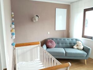 a living room with a blue couch and a crib at Mosel Cottage in Piesport in Piesport