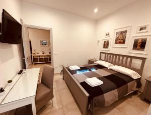 a bedroom with a bed with a desk and a television at Tannur Del Carmine in Noto