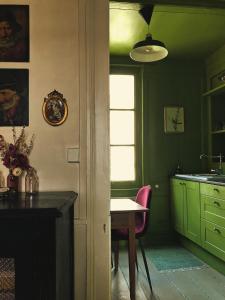 una cucina con mobili verdi e un tavolo con una sedia rosa di A Vol D'Oiseau a Honfleur