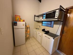 a small kitchen with a refrigerator and a microwave at Departamentos DE LA COSTA in Encarnación