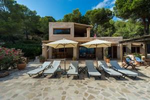 een groep stoelen en parasols op een terras bij amazing villa in Es Cubells