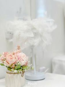 a white vase with pink flowers and a wine glass at Homestay NewLife Bãi Cháy in Ha Long +110 photos