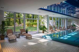 a house with a swimming pool and chairs and windows at Dolce by Wyndham Bad Nauheim in Bad Nauheim