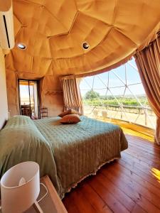 a bedroom with a large bed with a large window at Le Stelle di Elisa - Wine & Truffle Glamping in Suvereto