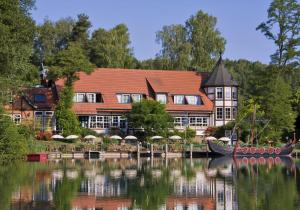 Romantischer Seegasthof & Hotel Altes Zollhaus في فيلدبرج: مبنى كبير مع قارب في الماء