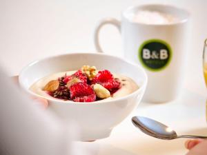 eine Person hält eine Schüssel Joghurt mit Beeren und Nüssen in der Unterkunft B&B HOTEL Düsseldorf-Mitte in Düsseldorf
