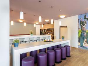 eine Lobby mit lila Hockern und einer Bar in einem Restaurant in der Unterkunft B&B HOTEL Düsseldorf-Mitte in Düsseldorf