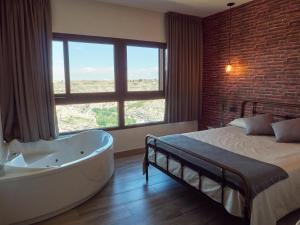 a bedroom with a tub and a bed and a window at Casas Rurales Maribel - Complejo Moradas del Cerro 2 - Suites con Jacuzzi en Alcalá del Júcar in Casas del Cerro