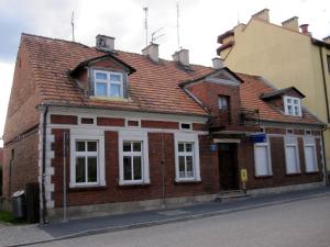an old brick building with white windows on a street at Marina Mikołajki in Mikołajki