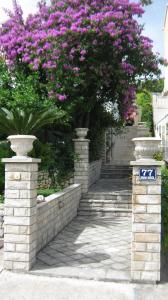 a set of stairs with pink flowers and a tree at Perun Guest House in Mlini