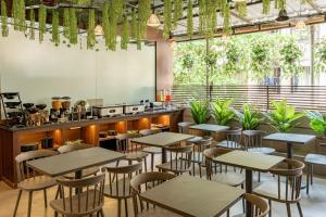 a restaurant with tables and chairs and plants at Hotel Dakshin Grandeur in Navi Mumbai