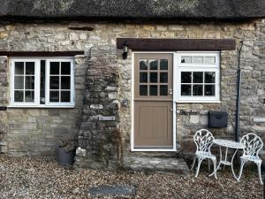 a stone cottage with a door and two chairs and a table at Bracken Cottage in Weymouth