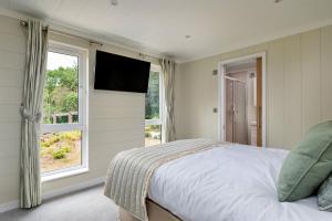 Un dormitorio con una cama y un televisor en una pared. en Finest Retreats - Cambridge Luxury Lodge,  25 fotos más